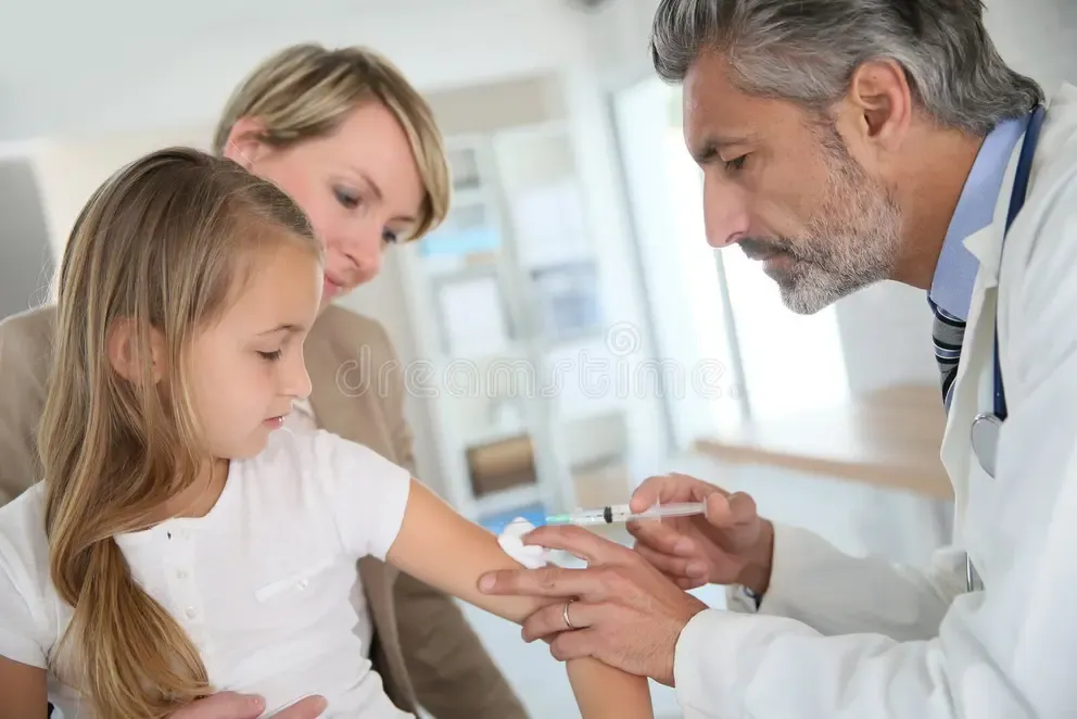 Doctor administering vaccine injection to a child supported by her mother in a pediatric clinic